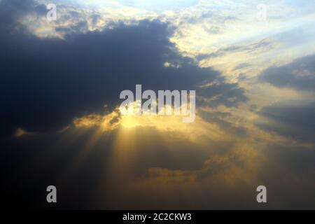 sun rays coming out from black clouds Stock Photo