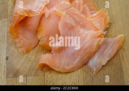 Slices of fresh smoked salmon on a wooden cutting board close up. Stock Photo