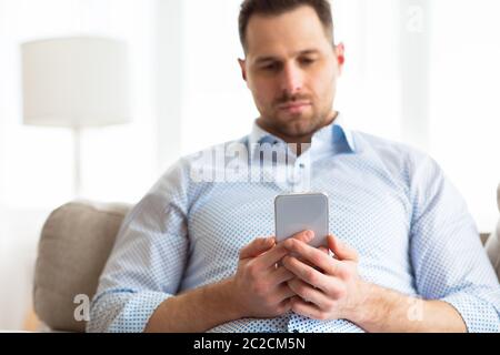 Bored adult man using smart phone at home Stock Photo