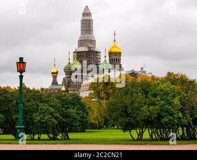 Church of the Saviour on Spilled Blood onion domes seen from Field of Mars park with scaffolding construction work, St Petersburg, Russia Stock Photo
