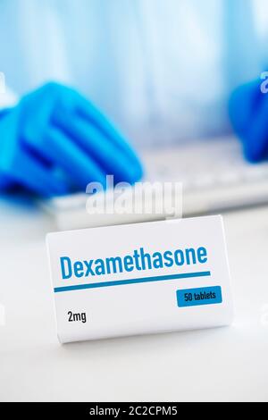 closeup of a simulated box of dexamethasone on a white table, and a man of a man wearing a white coat and blue surgical gloves in the background Stock Photo
