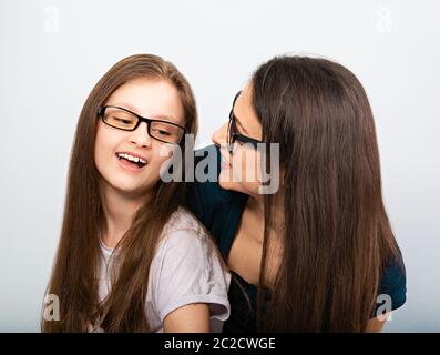 Young casual smiling mother talking with her happy kid in glasses hugging on light blue background. Closeup studio portrait. Teaching kids staying at Stock Photo