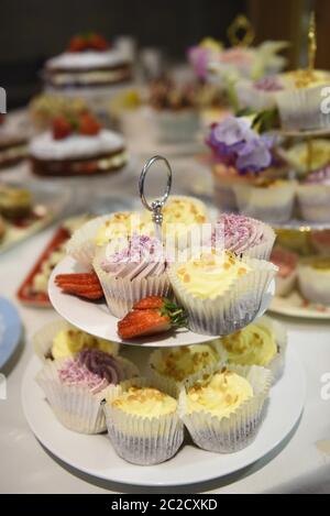 Fancy cakes on a cake stand at a buffet. Selective focus. Real life selection of tea and fairy cakes at a party celebration. Stock Photo