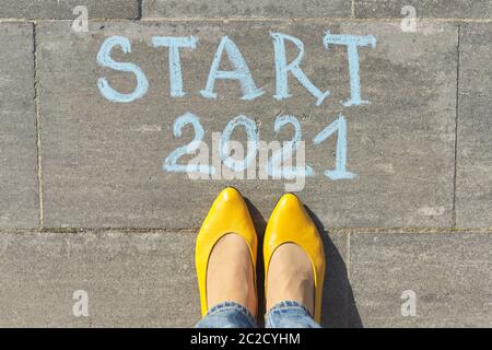 Start 2021 year concept, top view on woman legs and text written in chalk on gray sidewalk Stock Photo