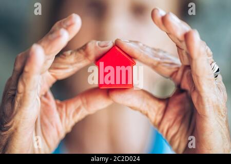 Elderly woman holding a small house in her hands Stock Photo