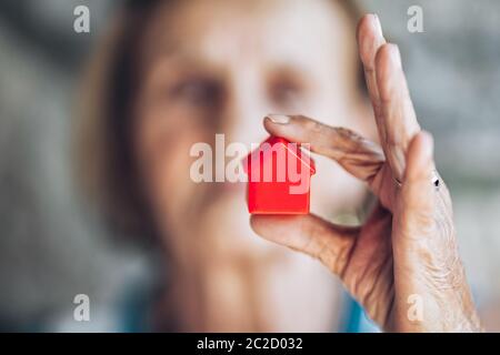 Elderly woman holding a small house in her hands Stock Photo
