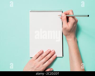 Blank paper notebook and female hands with pencil Stock Photo