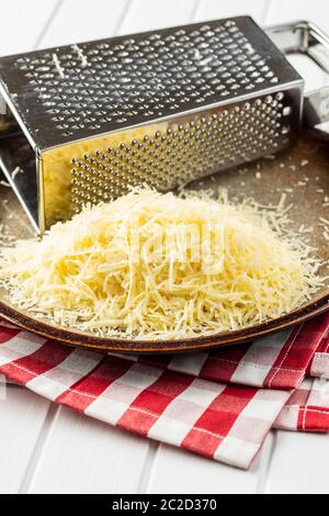 Tasty grated cheese. Parmesan cheese with grater on plate. Stock Photo