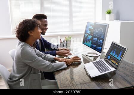 Stock Market Broker Analyzing Graphs On Computer In Office Stock Photo