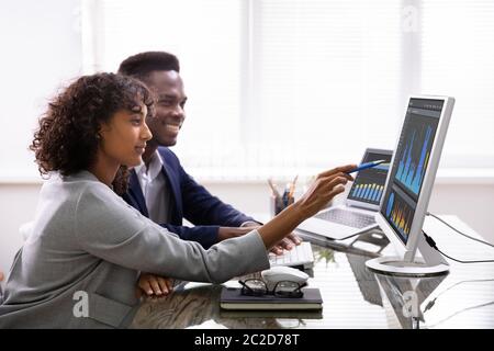 Stock Market Broker Analyzing Graphs On Computer In Office Stock Photo