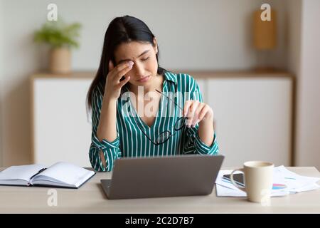 Businesswoman Touching Aching Eye Having Poor Eyesight Sitting In Office Stock Photo