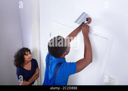 Technician Installing Security Camera System At Home Stock Photo