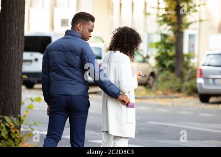 Robber Stealing Clutch From Woman Cardigan Pocket On Street Stock Photo