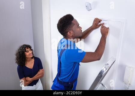 Technician Installing Security System Door Sensor On Wall Stock Photo