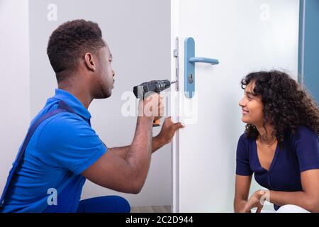 Technician Fixing The Door Lock At Clients Home Stock Photo