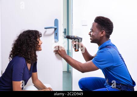 Technician Fixing The Door Lock At Clients Home Stock Photo
