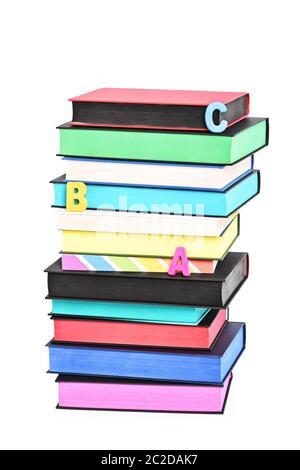 Stack of colorful books witch different sprayed edges and scattered letters spelling ABC, isolated on white background. Stock Photo
