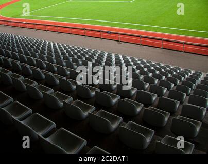 Rows of empty seats in a soccer sports stadium with green grass. Seen from above. Stock Photo
