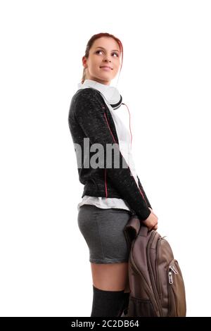 A portrait of a smiling female student in uniform with headphones, holding a backpack, isolated on white background. I can't wait to go back to school Stock Photo