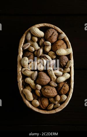 Nuts in basket. Mixed organic nuts in basket on black background. Group of different nuts Stock Photo