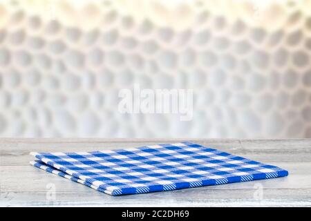 Closeup of a empty blue checkered tablecloth or napkin on a rustic bright gray table over abstract blurred  bright background. Template for food and p Stock Photo