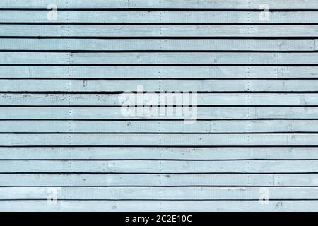 Pastel light blue painted, horizontal, slightly weathered board wall with three vertical rows of screws Stock Photo