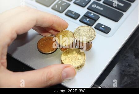 Hand putting golden colored Euro coin over laptop keyboard. Online shopping internet business concept Stock Photo
