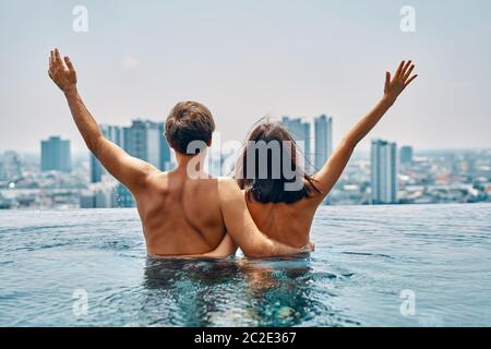 Young happy couple in love with arms up having fun in swimming pool Stock Photo