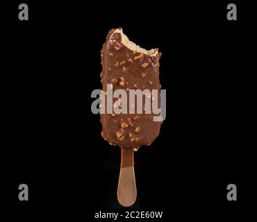 Bitten vanilla ice cream covered with chocolate and peanuts on black background Stock Photo