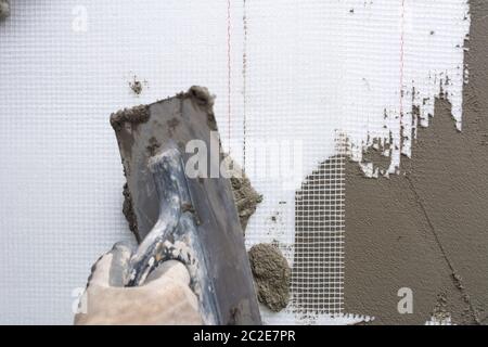 Closeup hand construction plastering wet cement on expanded polystyrene Stock Photo