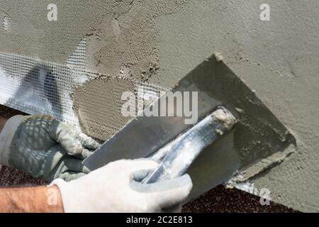 Closeup hand construction plastering wet cement on expanded polystyrene Stock Photo
