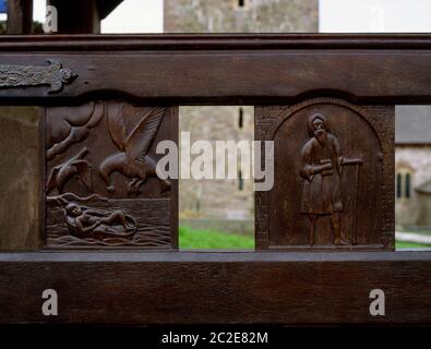 Scenes from the Life of St Kyned (Cenydd) carved on the modern wooden gates of the lychgate to his church at Llangennith, Gower, Wales, UK. Stock Photo