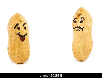 Smile and sad face drawn on dried peanuts on white background. Concept for good mood or bad mood Stock Photo