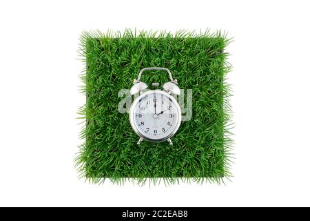 Old style alarm clock on square of green grass field isolated on white background with clipping path Stock Photo