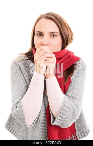 Portrait of a beautiful young woman wearing winter clothes, feeling cold and blowing warm air to her hands, isolated on white background. Stock Photo