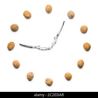 walnuts clock with nutcracker as hands on white background Stock Photo