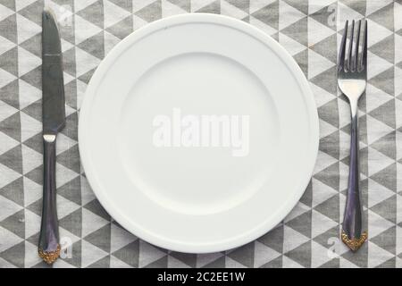 Clean empty white plate with knife and fork. Stock Photo