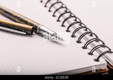 Opened notepad in a cage with an automatic plastic ballpoint pen close-up. Stock Photo