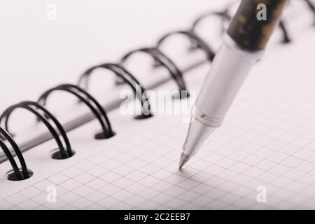 Opened notepad in a cage with an automatic plastic ballpoint pen close-up. Stock Photo
