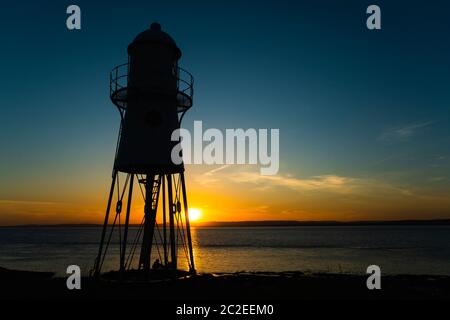 Black Nore Lighthouse in Portishead, Somerset, UK, at sunset on a summer evening with the Welsh coastline in the distance. Stock Photo