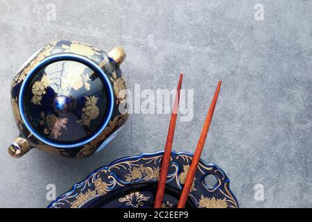 Empty plate, teapot with herbal tea and chopsticks over table Stock Photo