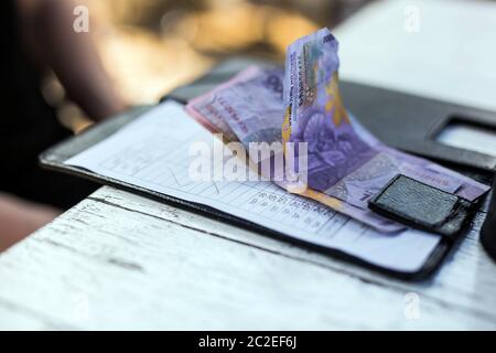 Restaurant bill with money on payment tray on the table, money is rupiah colors Stock Photo