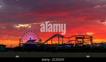 Pacific Park amusement park on the Santa Monica Pier under a fiery sky due to the colourful evening sunset. Stock Photo