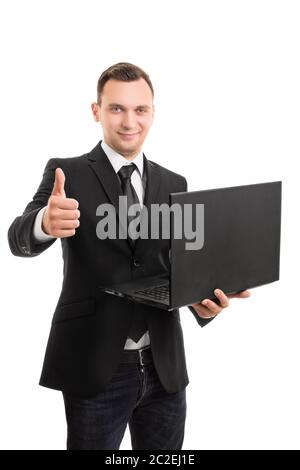 A portrait of a young businessman in a suit holding a laptop and giving thumbs up, isolated on white background. Stock Photo