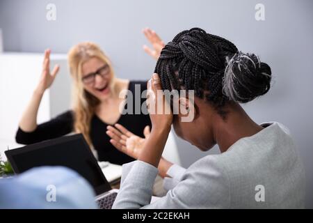 Rear View Of A Sad African Businesswoman Sitting In Front Of Her Boss Blaming Stock Photo