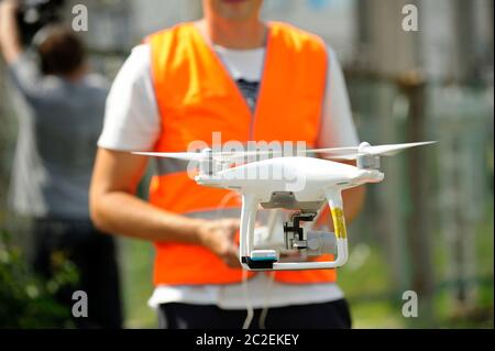 pro quadcopter with camera aboard flying, operator controlling it on the background Stock Photo