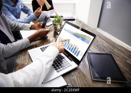 Side View Of Businesspeople Examining Graph On Computer At Workplace Stock Photo