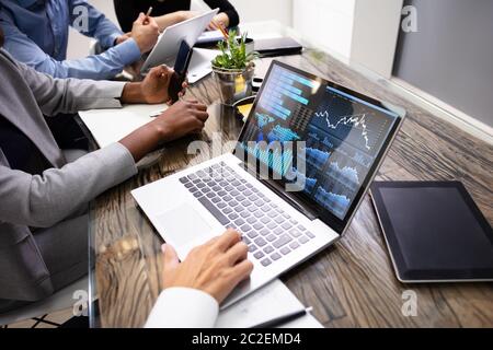 Side View Of Businesspeople Examining Graph On Computer At Workplace Stock Photo