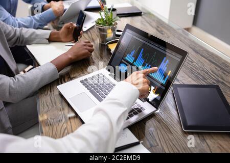 Side View Of Businesspeople Examining Graph On Computer At Workplace Stock Photo