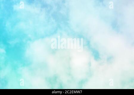Abstract background of a vibrant teal blue sky with soft puffy clouds Stock Photo